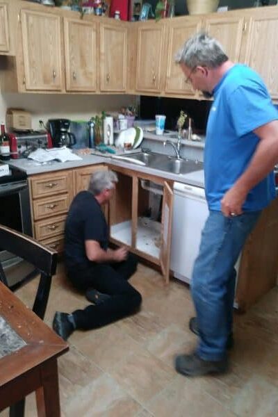 plumber working under kitchen sink during Moen faucet installation and PEX conversion