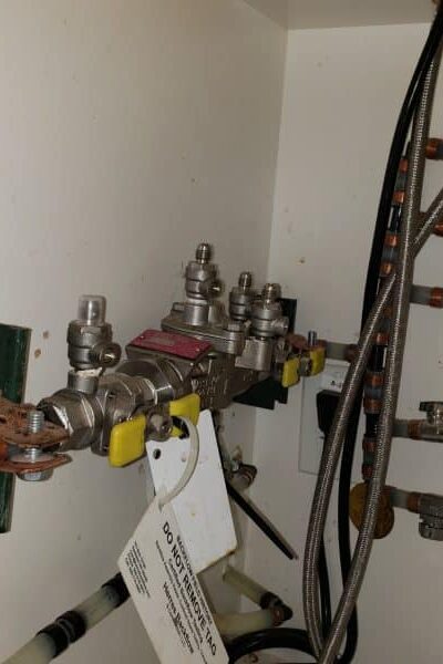 backflow valve under cabinet showing leak and water discharge before repair