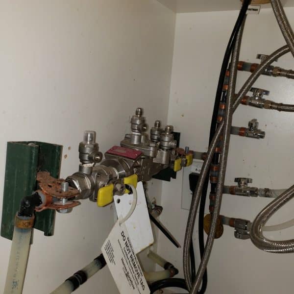 backflow valve under cabinet showing leak and water discharge before repair