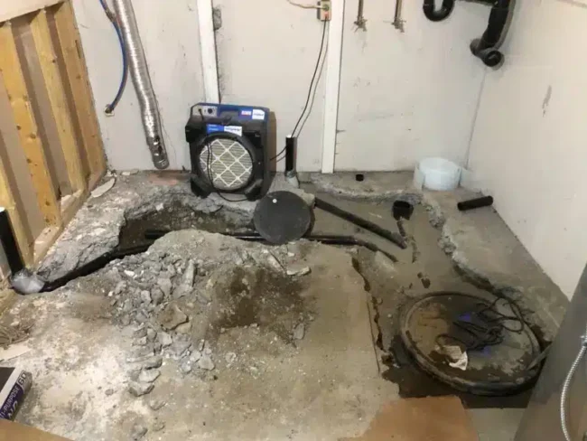 basement floor opened to install sewage ejector pump and underground plumbing