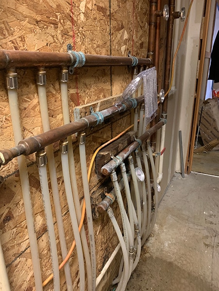 leaking hydronic manifold section with visible water damage before repair