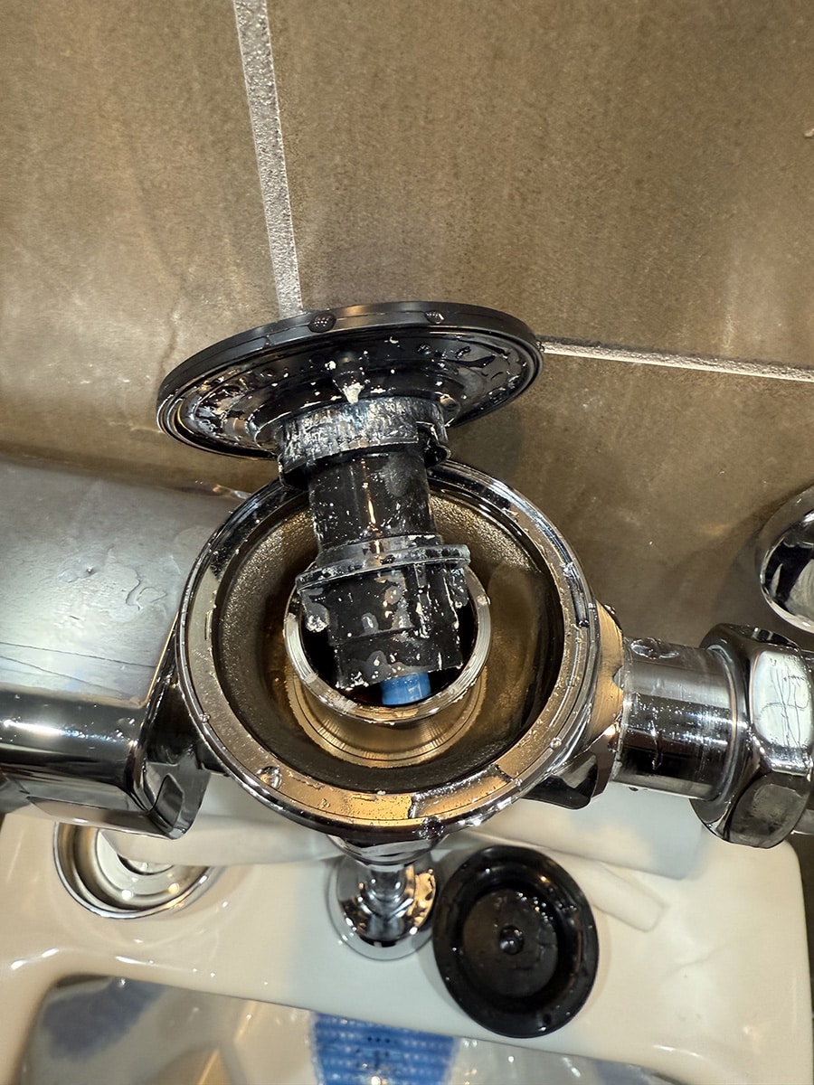 inside of automatic urinal flush valve showing sealant debris affecting internal components
