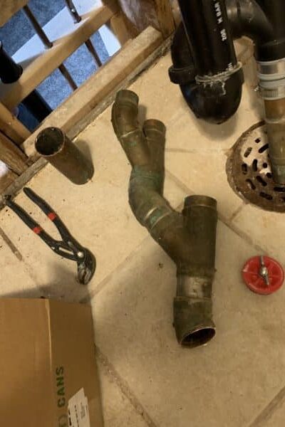 old copper drain pipe with visible corrosion and leak in residential plumbing system