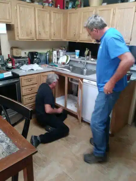plumber working under kitchen sink during Moen faucet installation and PEX conversion
