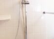 Moen slide bar with handheld shower head installed on tiled shower wall