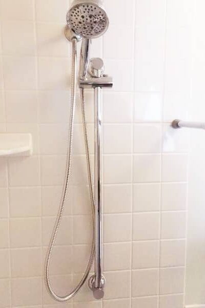 Moen slide bar with handheld shower head installed on tiled shower wall