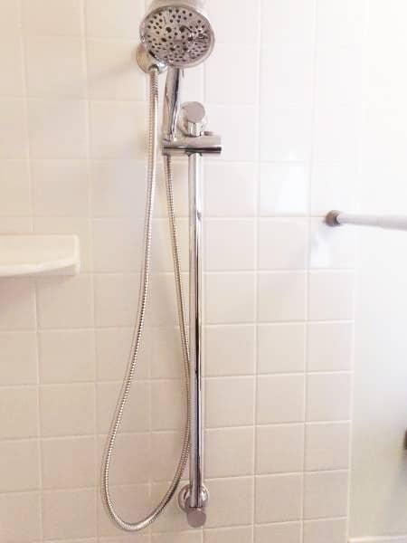 Moen slide bar with handheld shower head installed on tiled shower wall