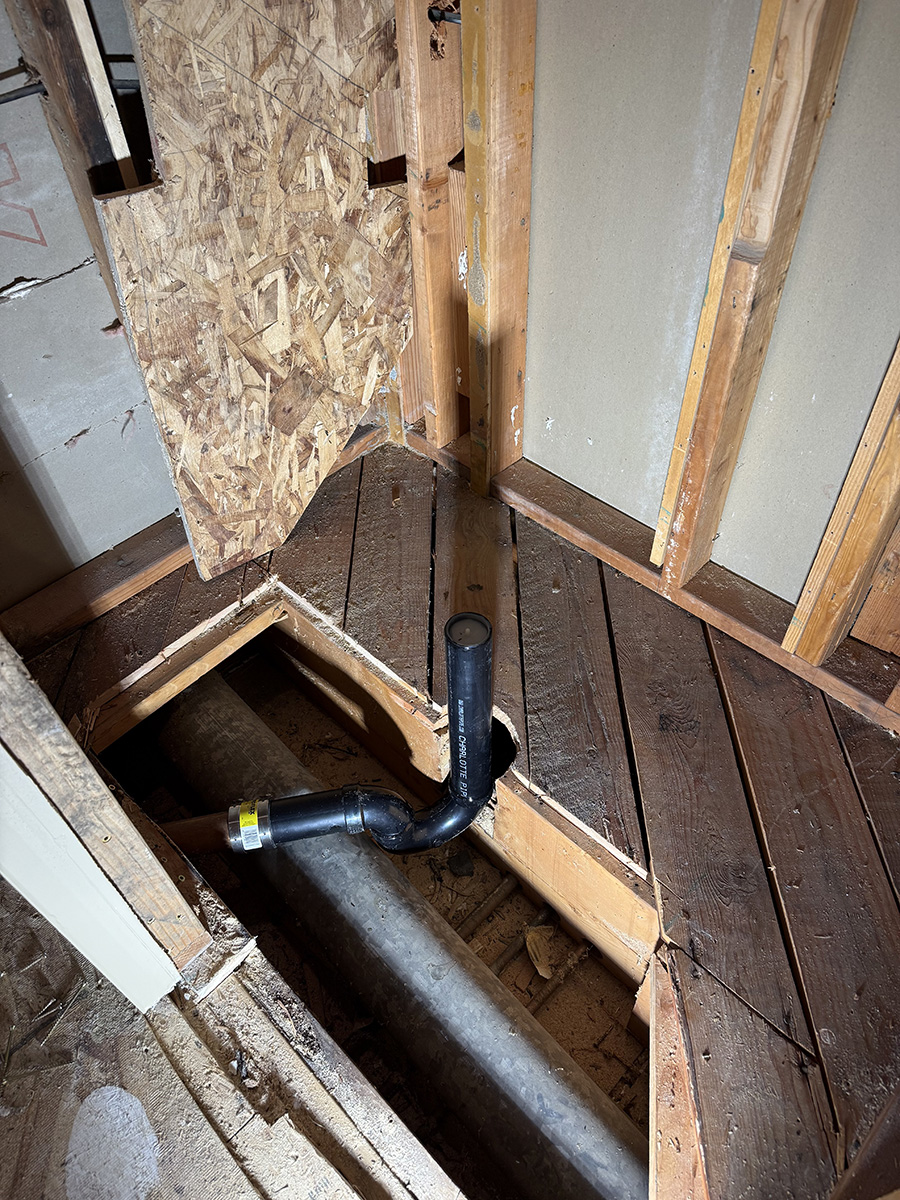 post-falls-abs-shower-drain-installation new ABS shower drain piping installed through open bathroom floor before tile shower construction