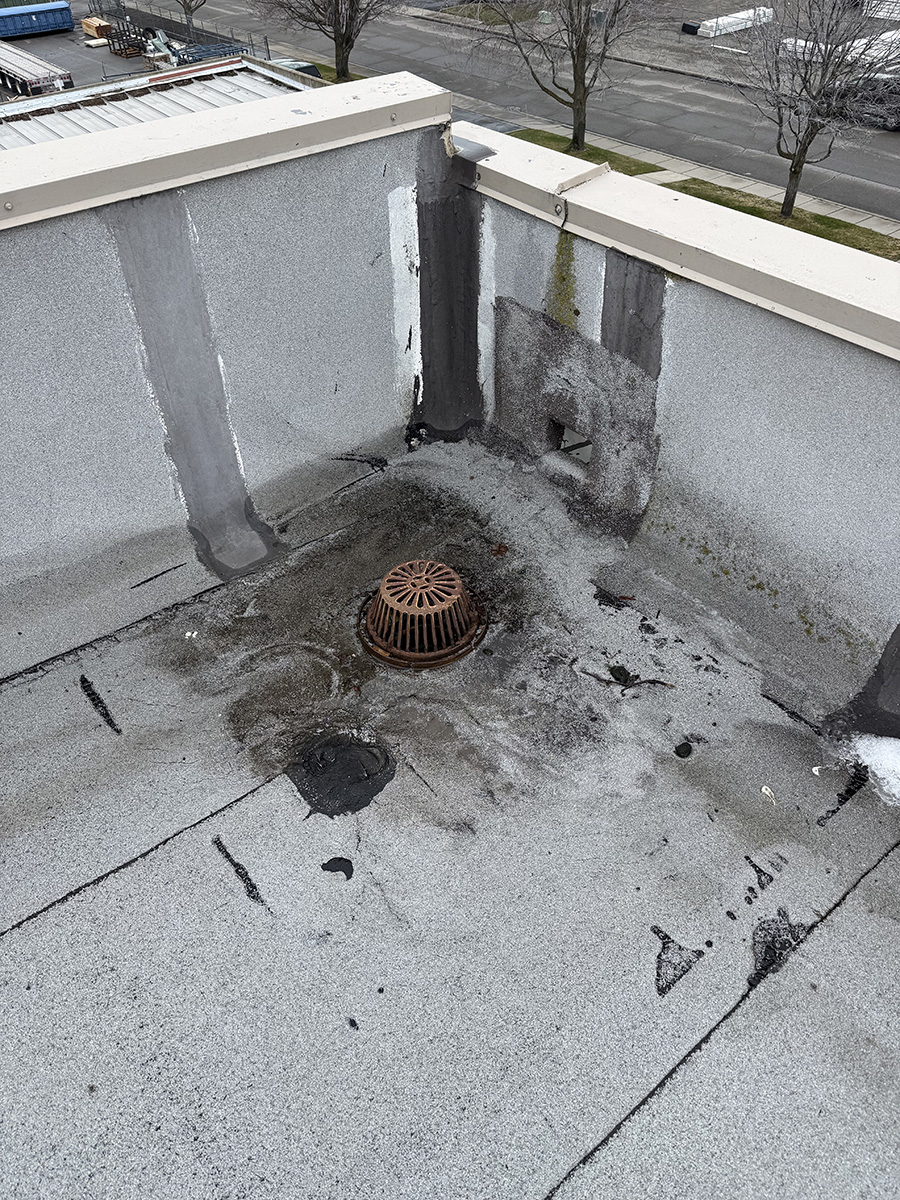 commercial rooftop drain area with staining and signs of leak near drain
