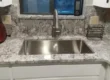 undermount stainless steel sink and faucet installed with granite countertops