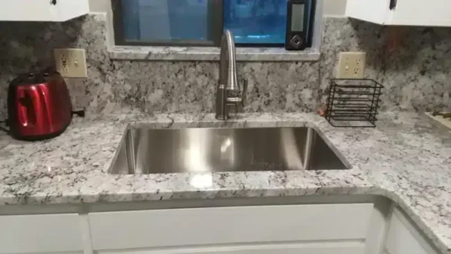 undermount stainless steel sink and faucet installed with granite countertops